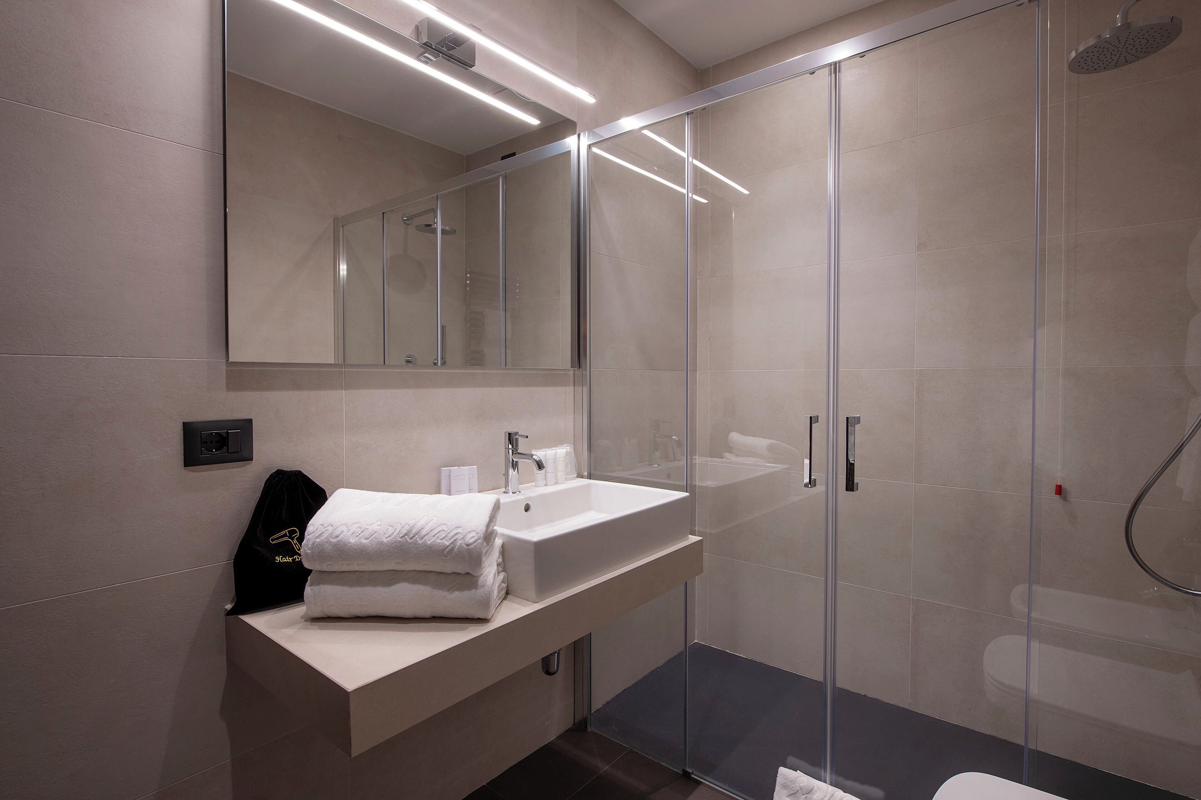 A modern bathroom with a glass-enclosed shower, a white sink, and a mirror above the vanity.