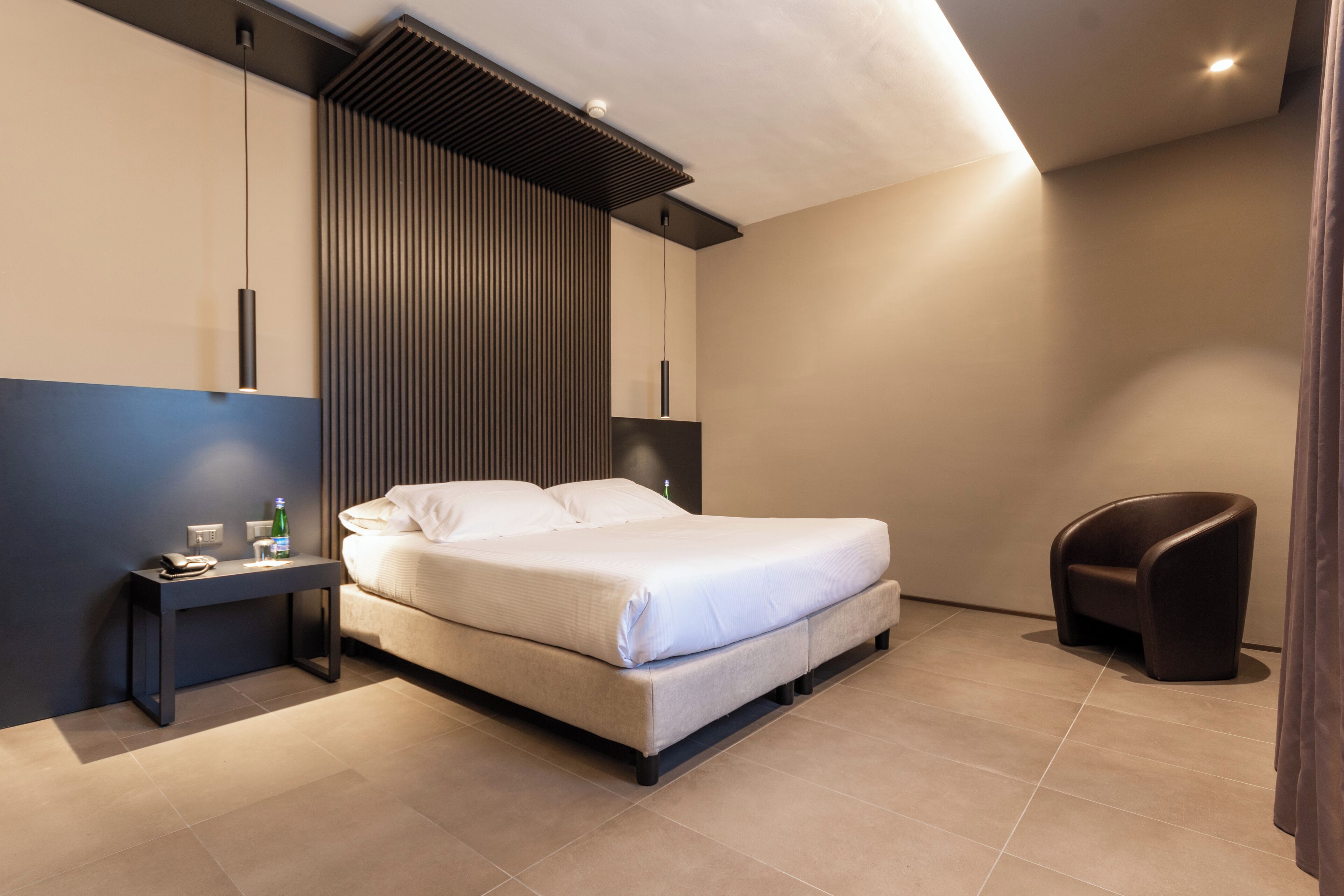 A modern bedroom with a bed, bedside table, and a chair.