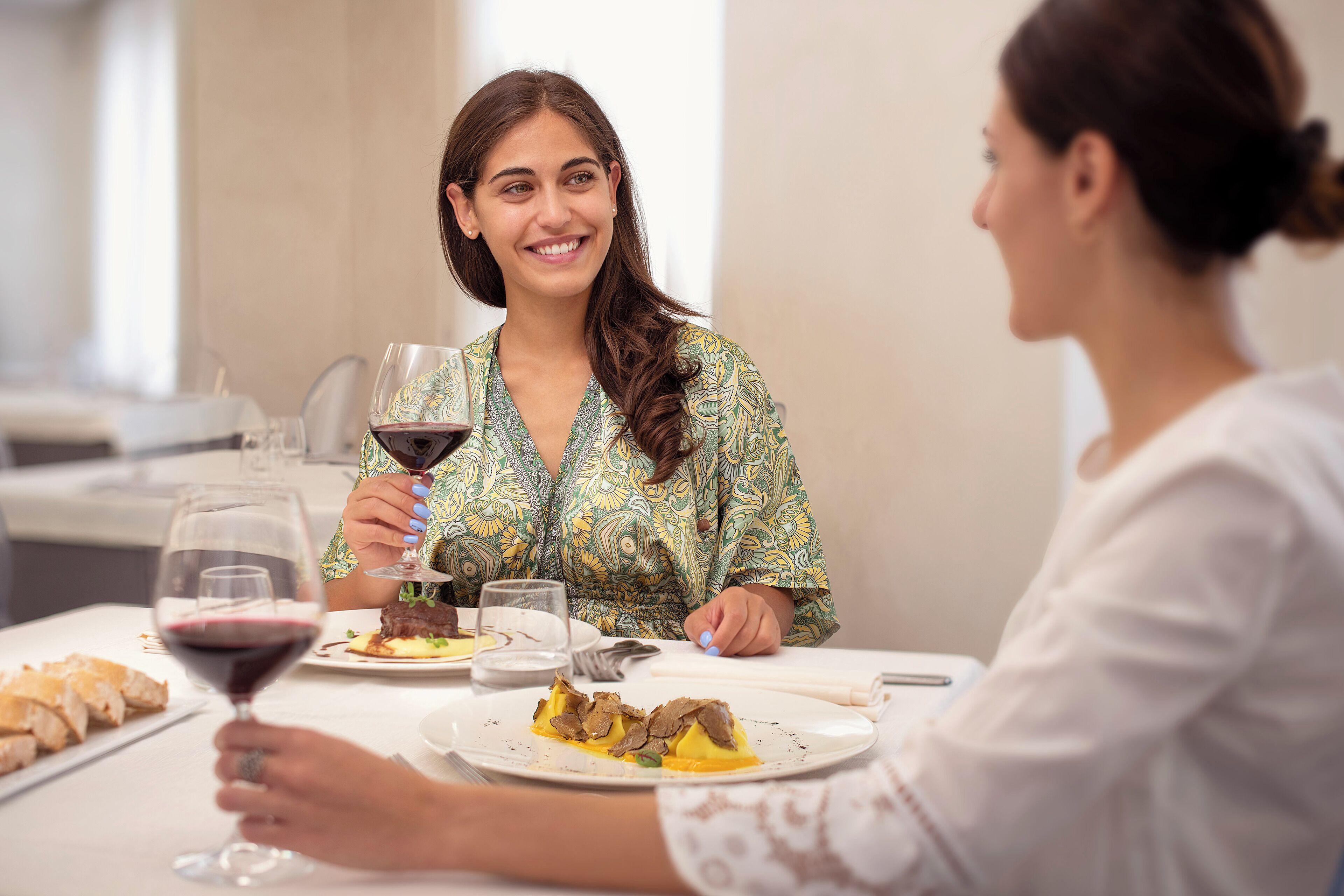 A dining table with plates of food and wine glasses.