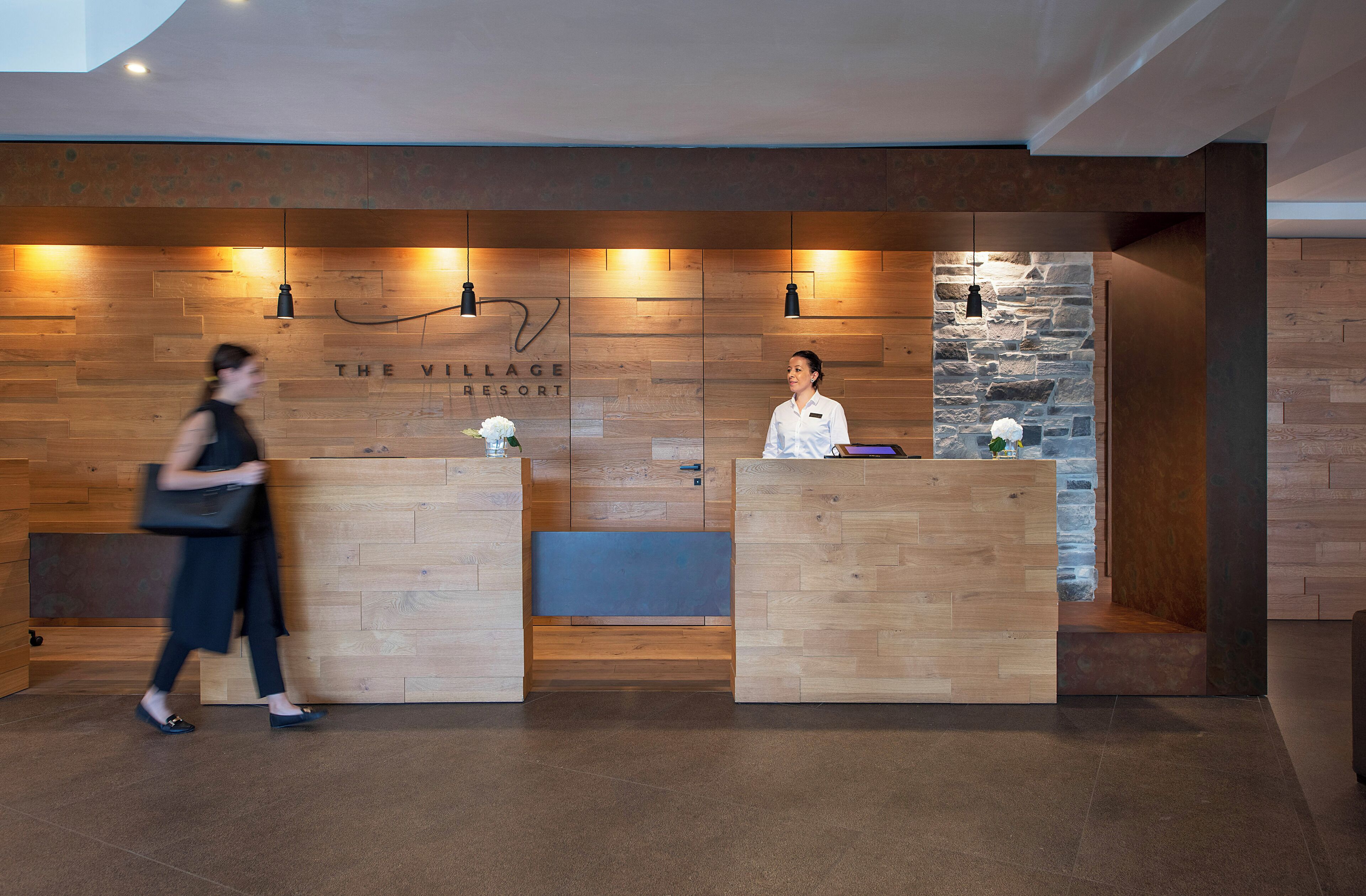 Un área de recepción con paneles de madera y una pared de acento de piedra, con un letrero que dice "THE VILLAGE RESORT".