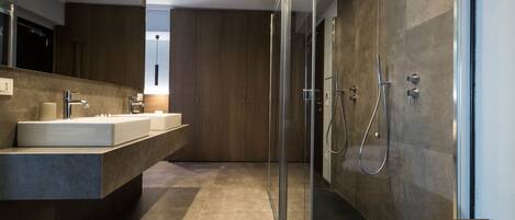 A modern bathroom with a glass shower enclosure, a large mirror, and a built-in sink.
