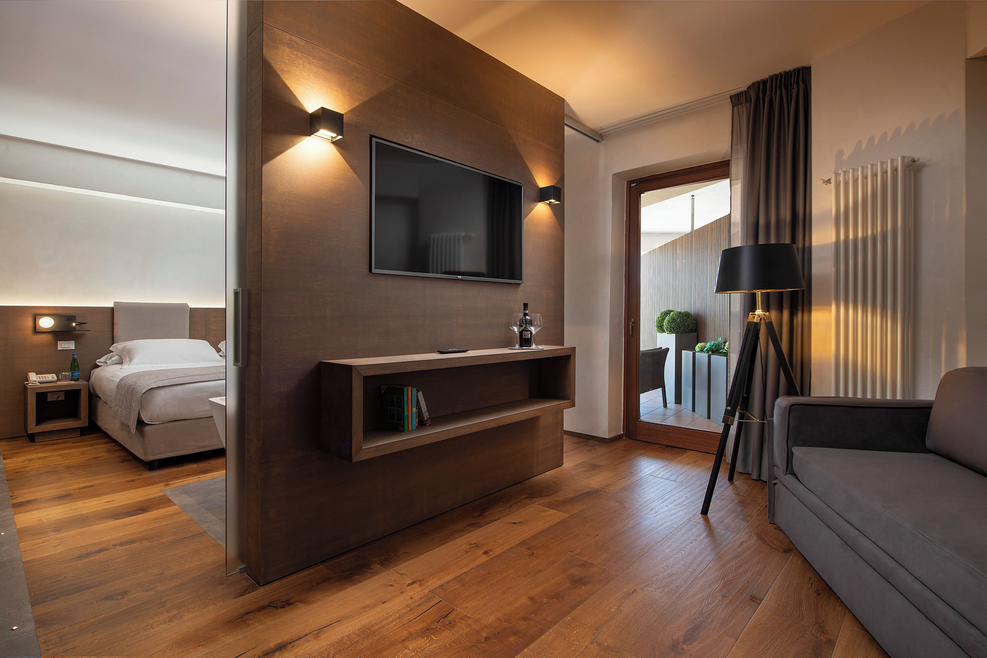 A modern living room with a flat-screen TV mounted on a wooden wall, a sofa, a coffee table, and a floor lamp.