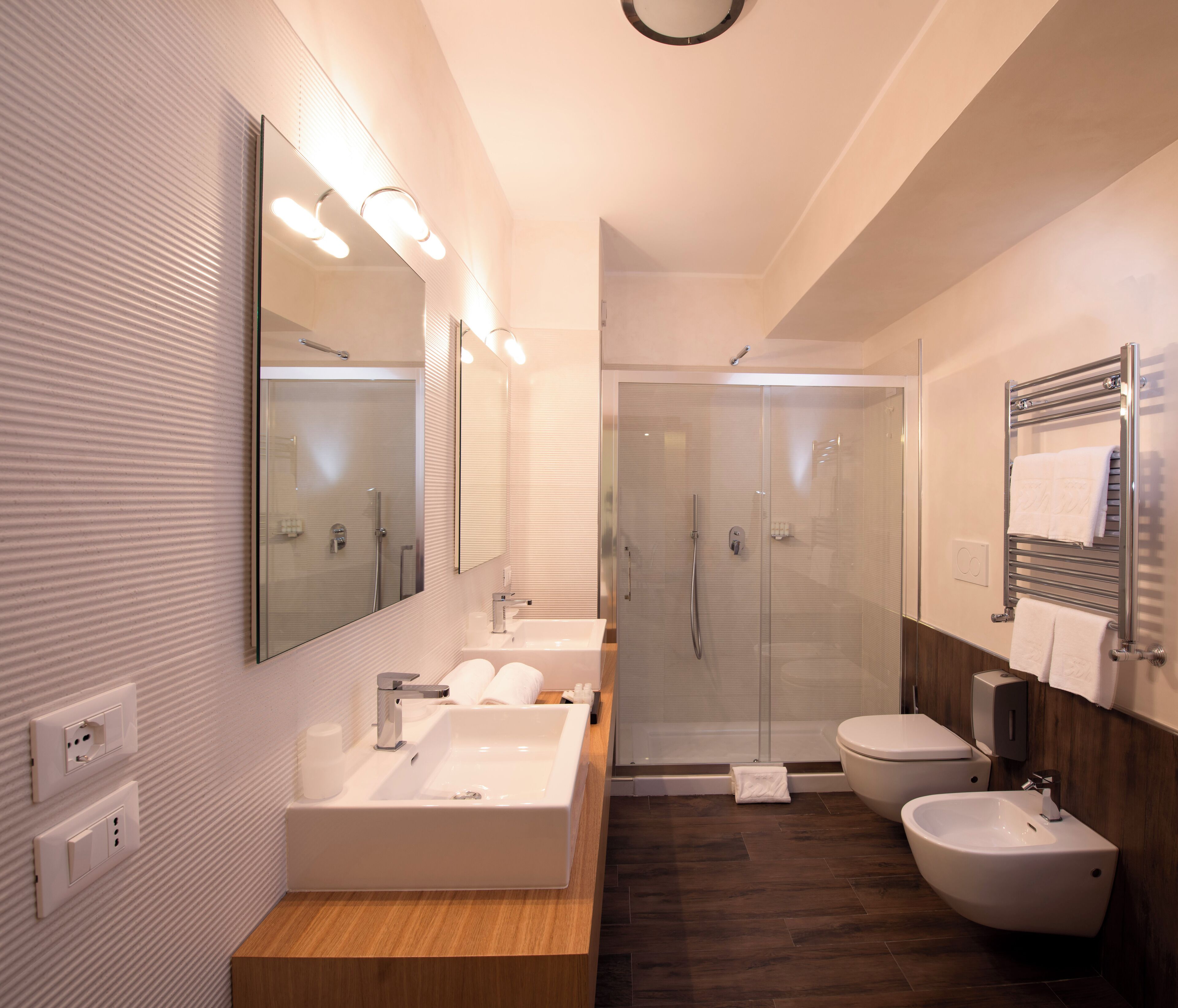 Une salle de bain moderne dotée d’une grande baignoire, d’un lavabo séparé, d’un bidet et d’une douche à parois de verre.