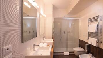Une salle de bain moderne dotée d’une grande baignoire, d’un lavabo séparé, d’un bidet et d’une douche à parois de verre.