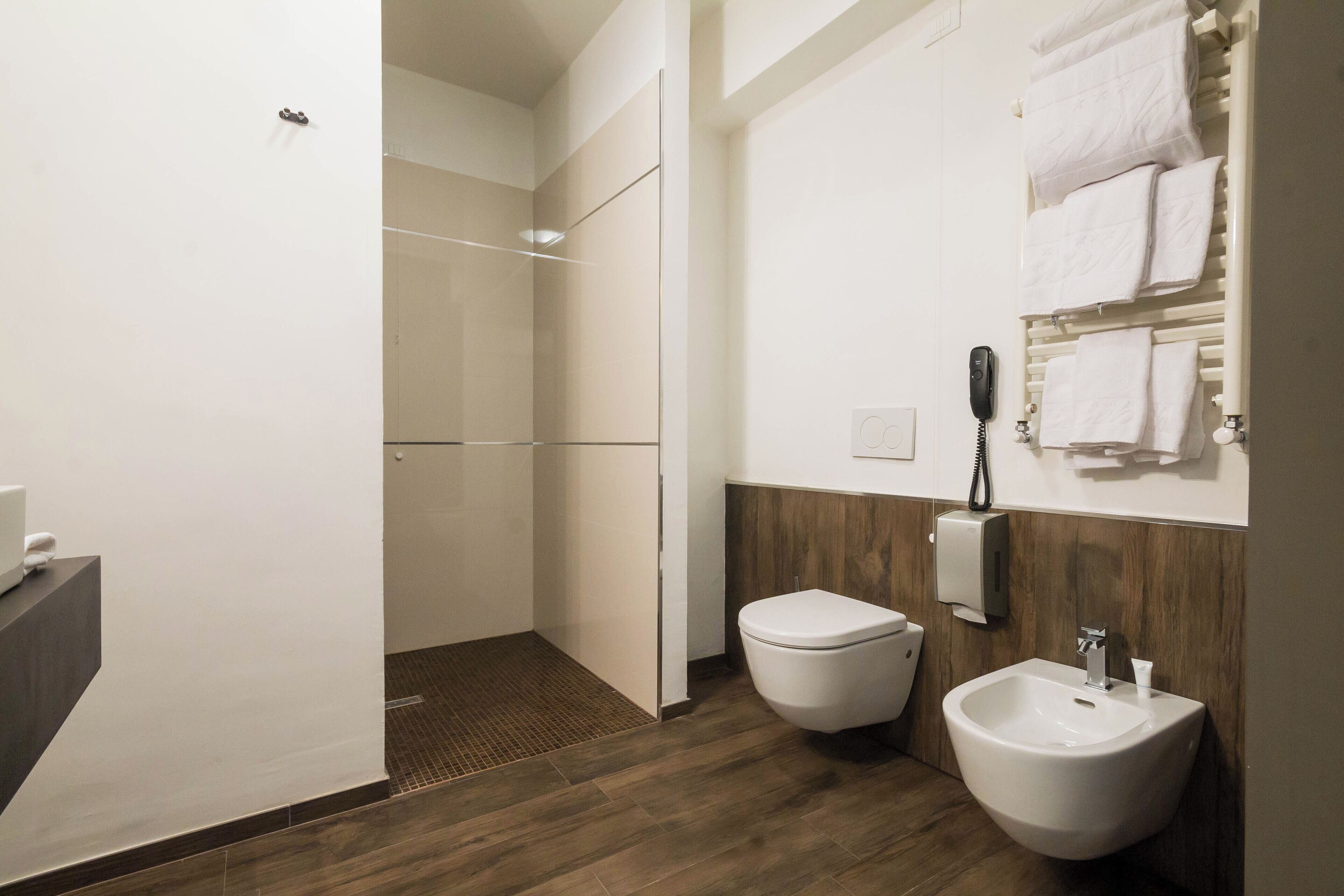 Un baño moderno con ducha, inodoro, bidé y perchero para toallas.