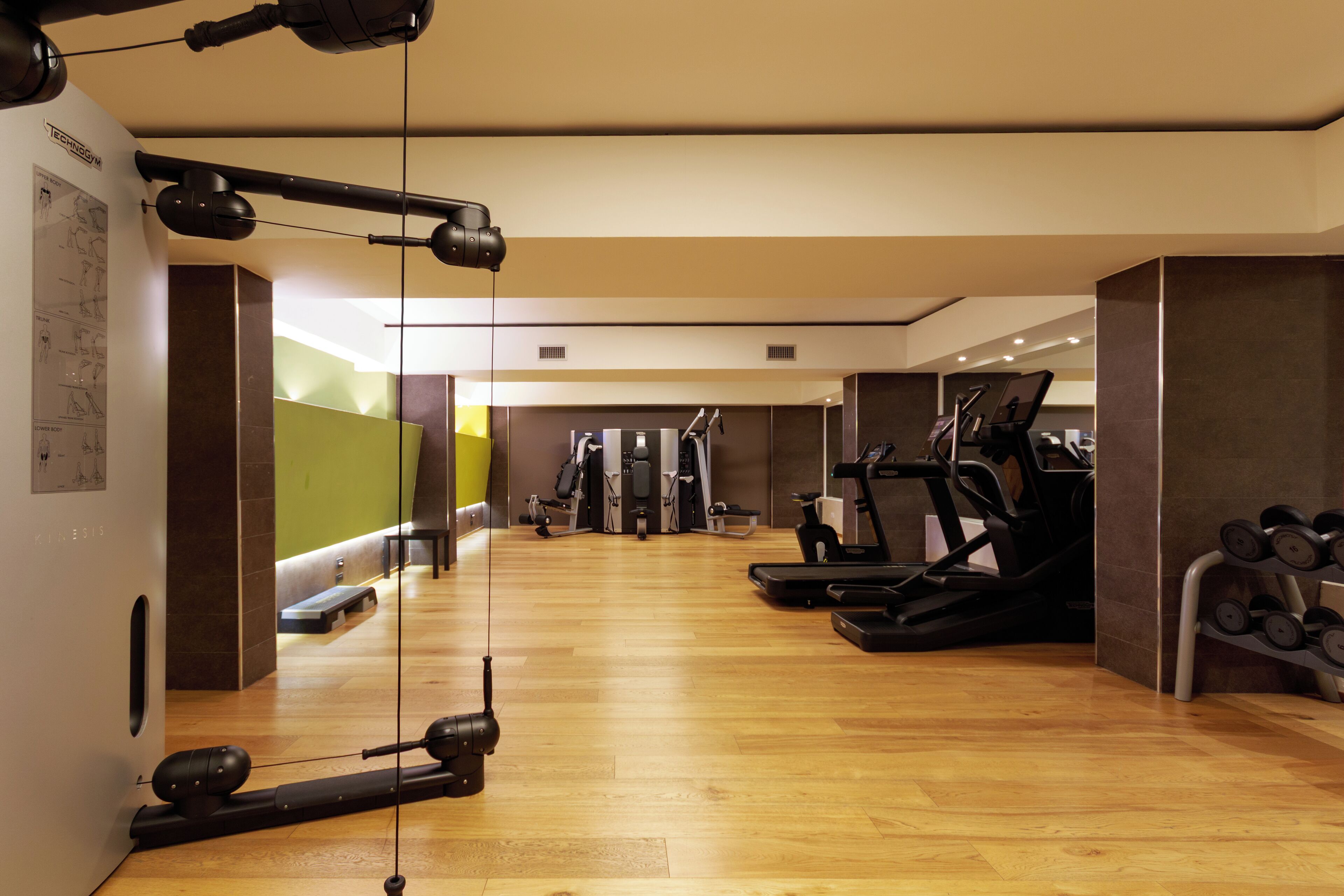 A gym with exercise equipment, a treadmill, and a rack of dumbbells.