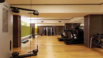 A gym with exercise equipment, a treadmill, and a rack of dumbbells.