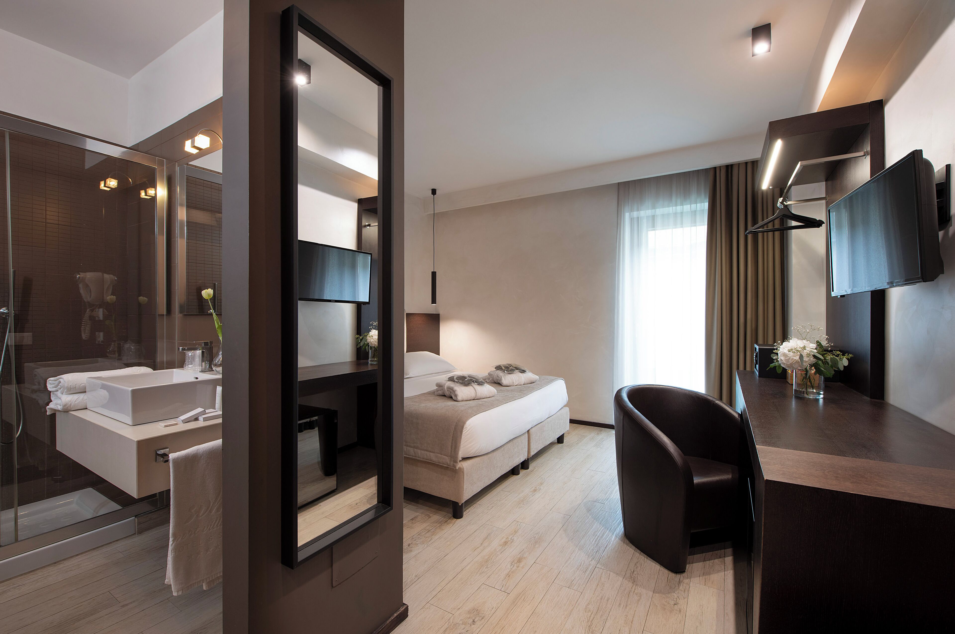 Une chambre d’hôtel moderne équipée d’un grand lit, d’un bureau, d’une télévision et d’une salle de bain avec douche et lavabo.