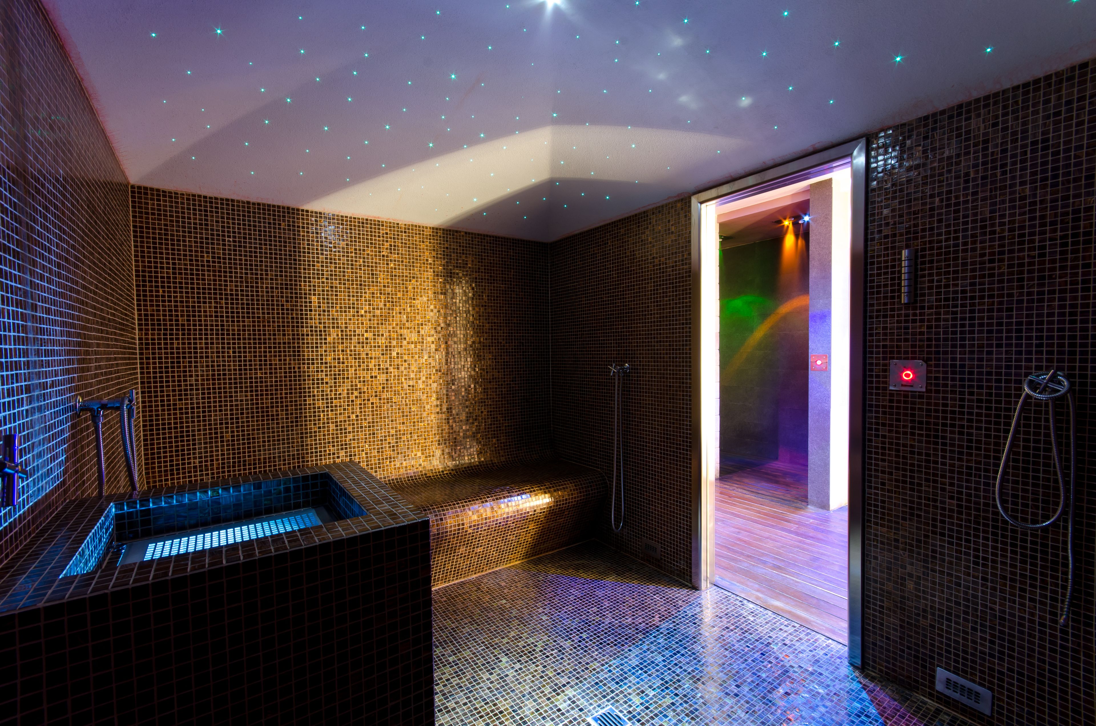 A modern bathroom with mosaic tile walls, a built-in bathtub, and a shower area.