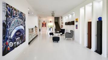 A modern interior with a staircase, a seating area, and a large artwork on the wall.