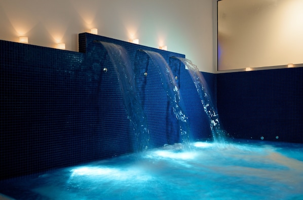 A spa area with a blue tiled wall and a water feature.