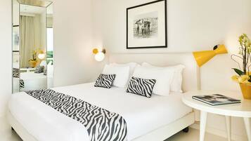 Une chambre d’hôtel avec un grand lit, une table de chevet avec une lampe, un tableau encadré au mur et un miroir.