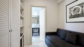 A modern living room with a dark grey sofa and a framed black and white photograph on the wall.