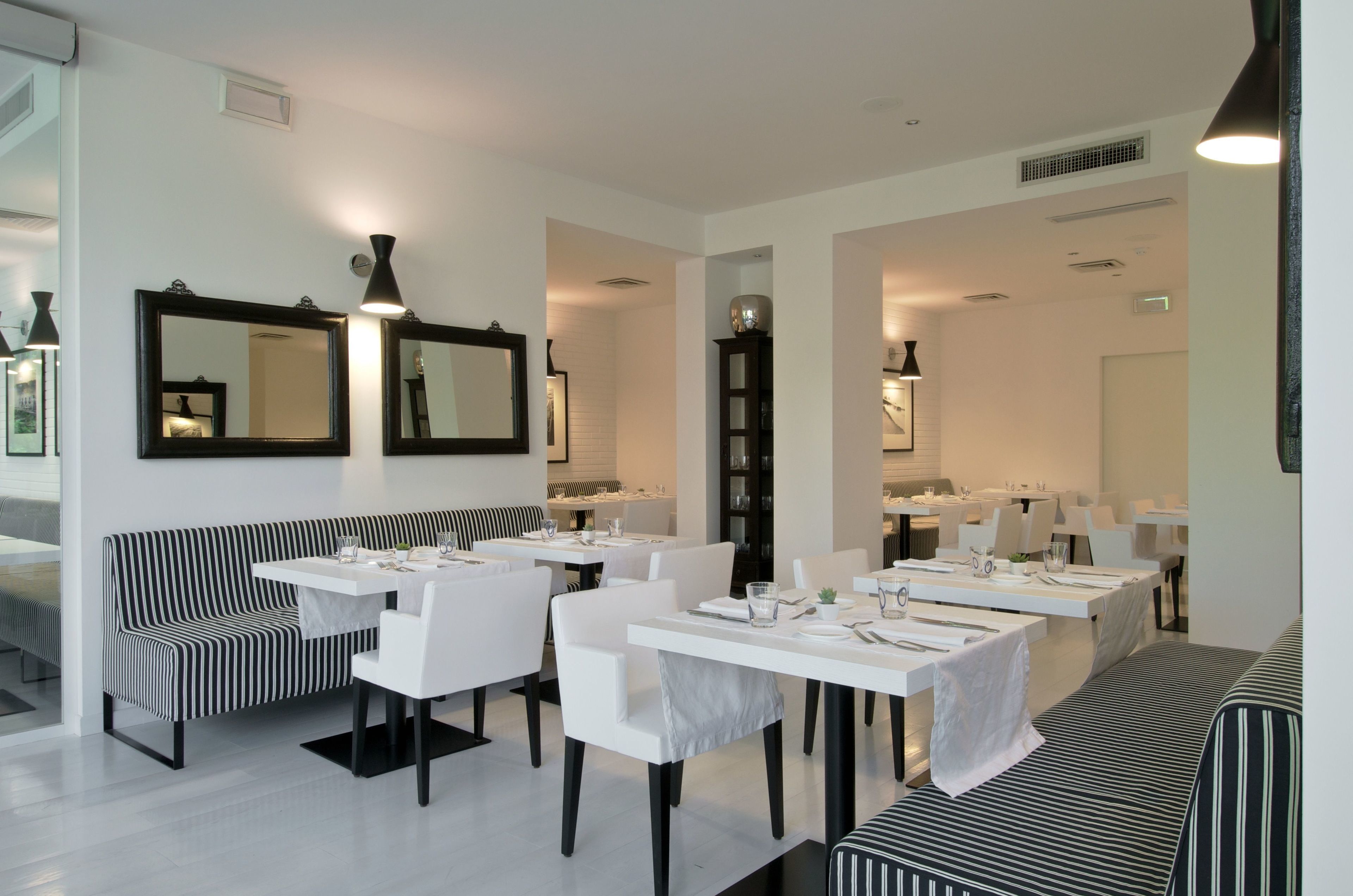 Un comedor moderno con sofás a rayas, mesas blancas y sillas negras.