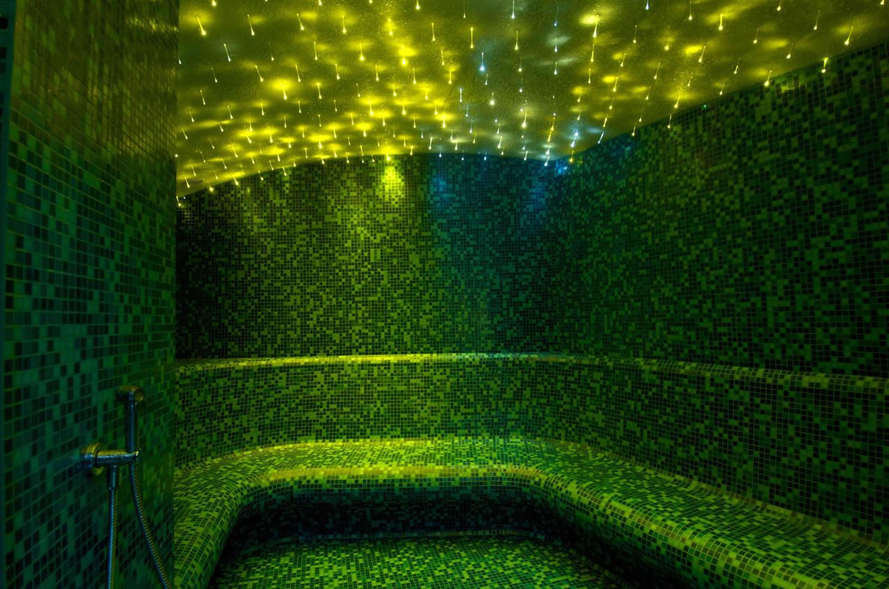A room with mosaic tile walls and a curved bench.