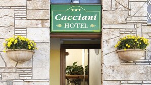 The entrance to the Cacciani Hotel with a stone facade, a sign above the door, and two flower planters on either side. - Cacciani Hotel (Frascati)