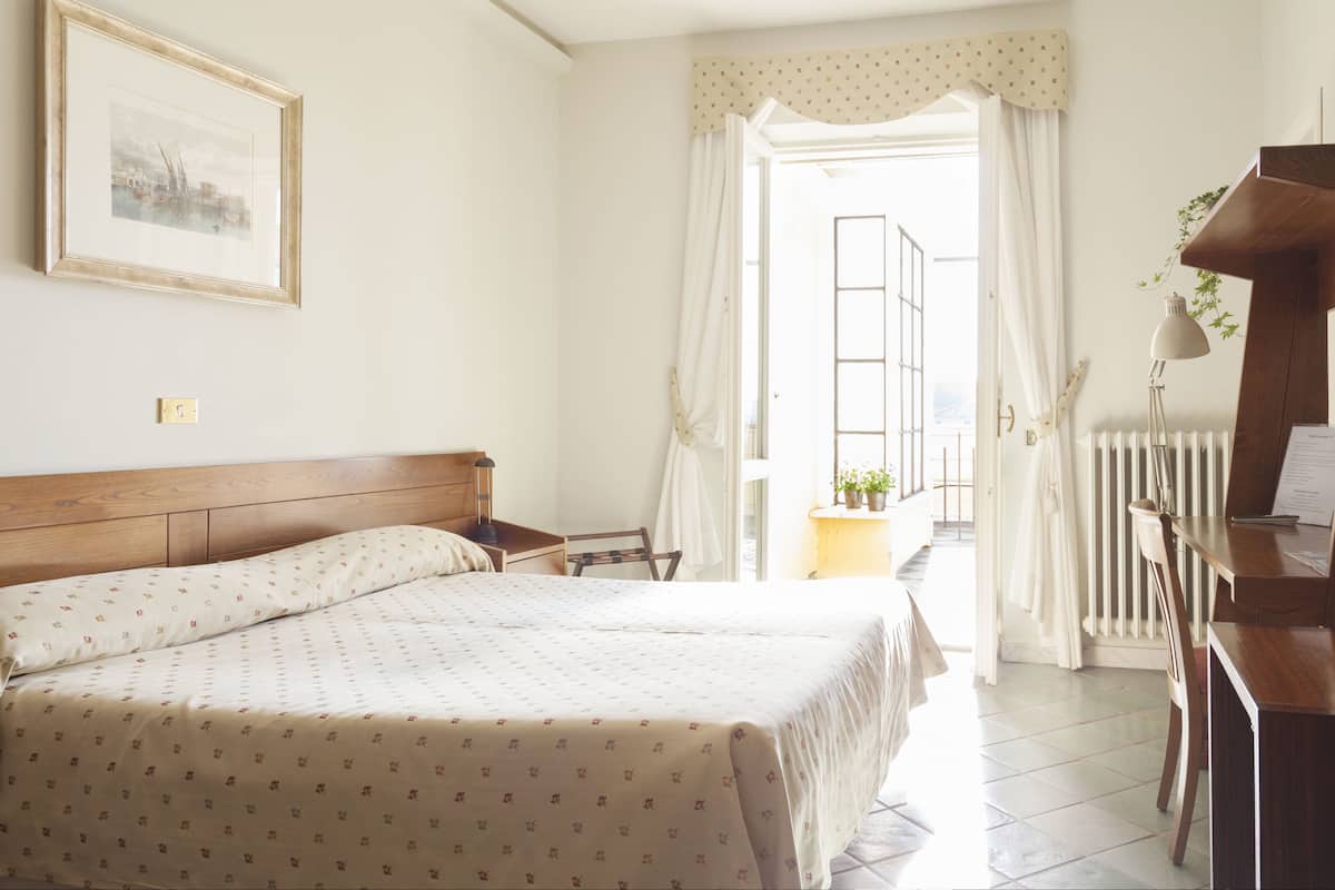 Une chambre à coucher avec un lit, un bureau, une chaise et une fenêtre avec des rideaux.