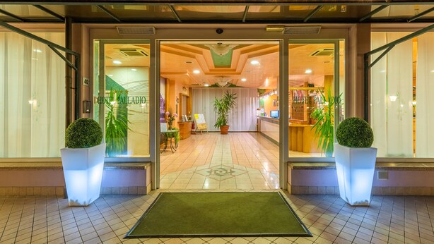 A hotel entrance with a reception desk, potted plants, and a tiled floor. - Hotel Palladio (Mestre)