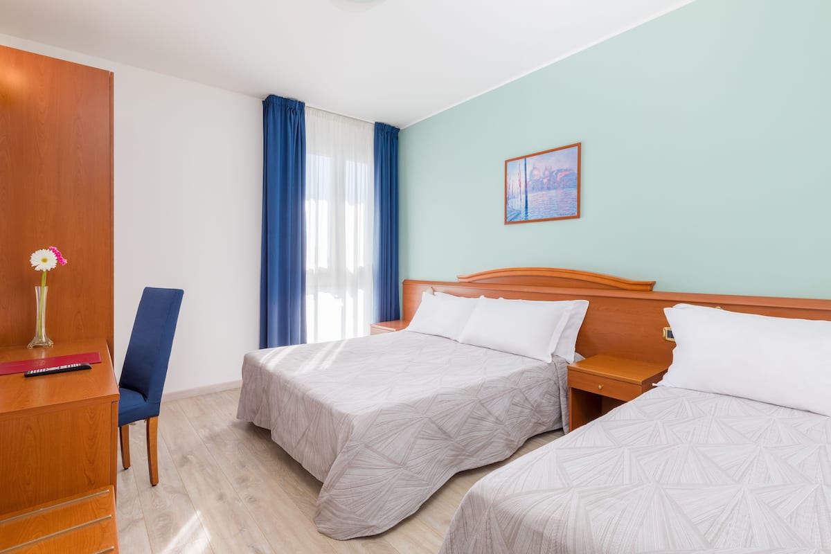 A hotel room with two beds, a desk, a chair, and a nightstand.