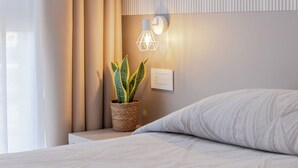 A bedroom with a bed, a bedside plant, a wall-mounted light fixture, and a power outlet. - Hotel Palladio (Mestre)