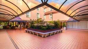 A spacious atrium with a central garden, tiled floor, and a modern architectural design with a glass ceiling. - Hotel Palladio (Mestre)