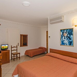 A hotel room with two beds, a television, a wooden chair, a painting, and an air conditioning unit.
