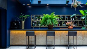 A bar area with a counter, three stools, and various plants. - 1K Paris (Paris)