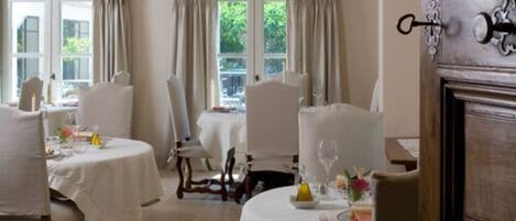 A dining area with round tables, white tablecloths, and chairs.