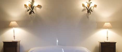 A bedroom with a large bed, two nightstands, and wall-mounted lamps.