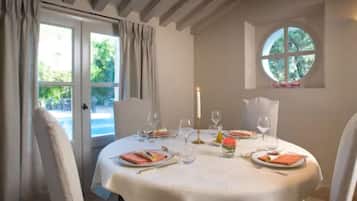 Mesa de comedor dispuesta para cuatro con mantel blanco, velas y copas de vino.