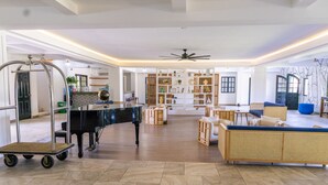 Un amplio espacio de sala con un piano, un sofá y una estantería.
