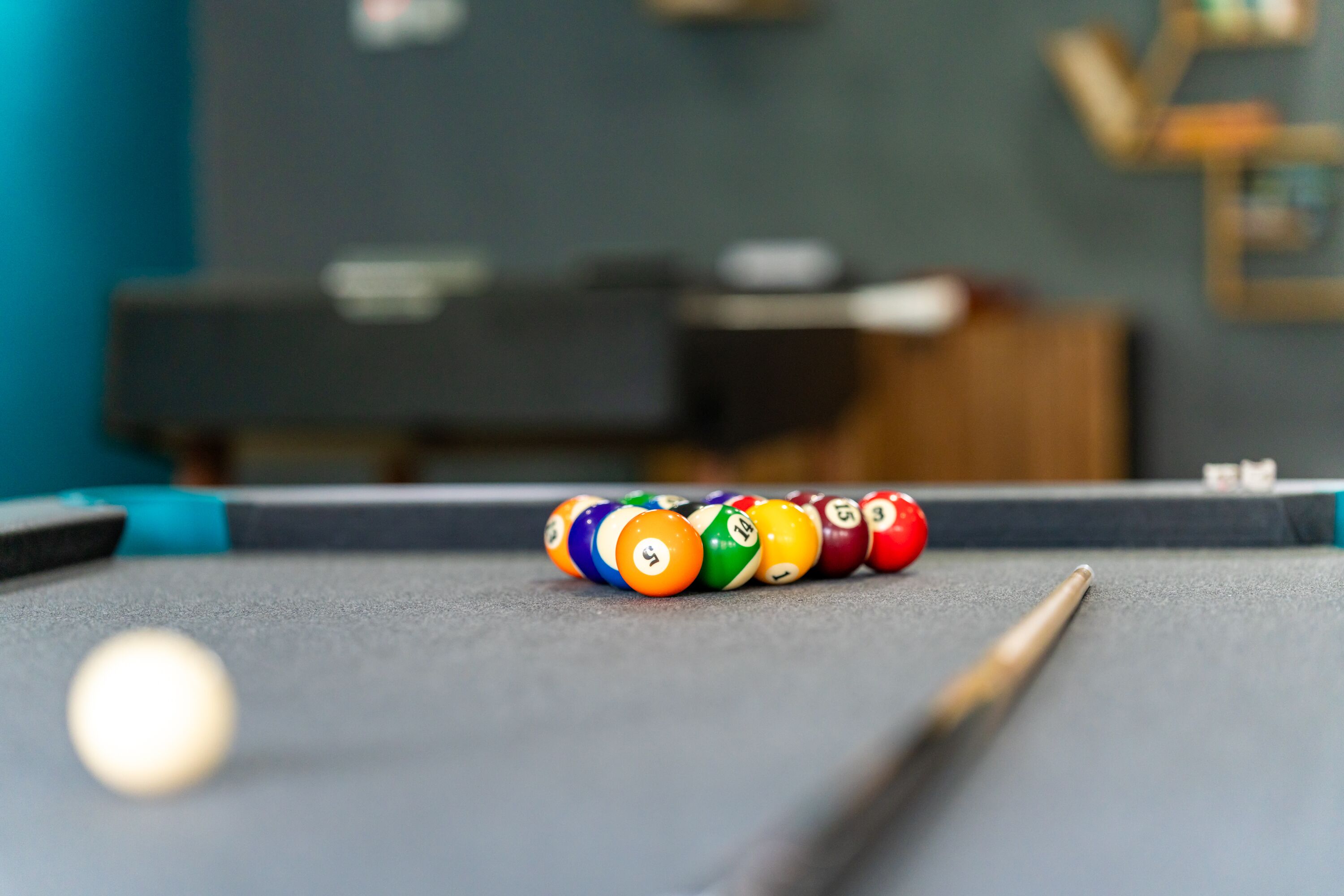 A pool table with a cue stick and billiard balls.