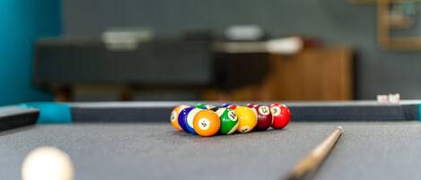 A pool table with a cue stick and billiard balls.