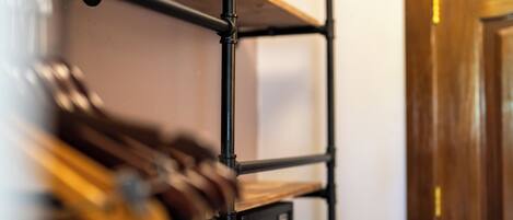 Una estantería metálica con repisa superior de madera y un dispositivo electrónico negro debajo.