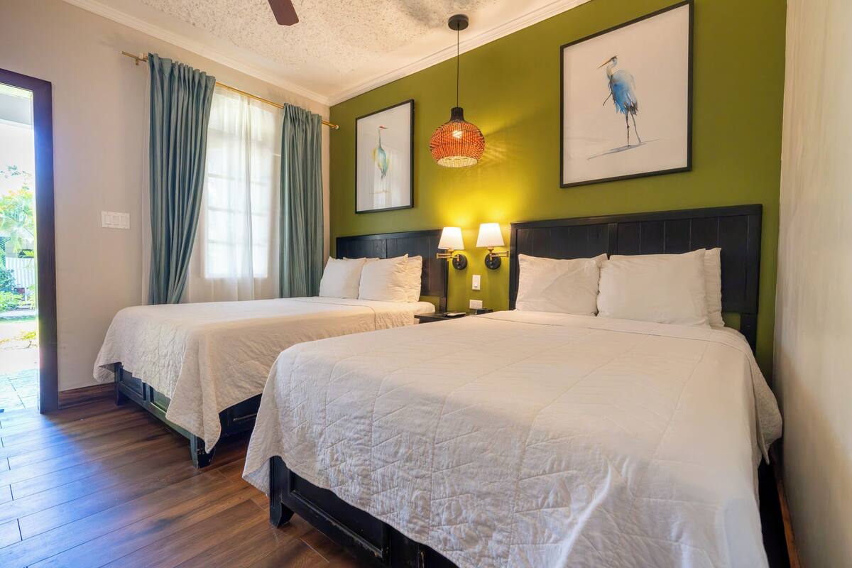 Une chambre d’hôtel avec deux lits, un mur vert et des œuvres d’art.