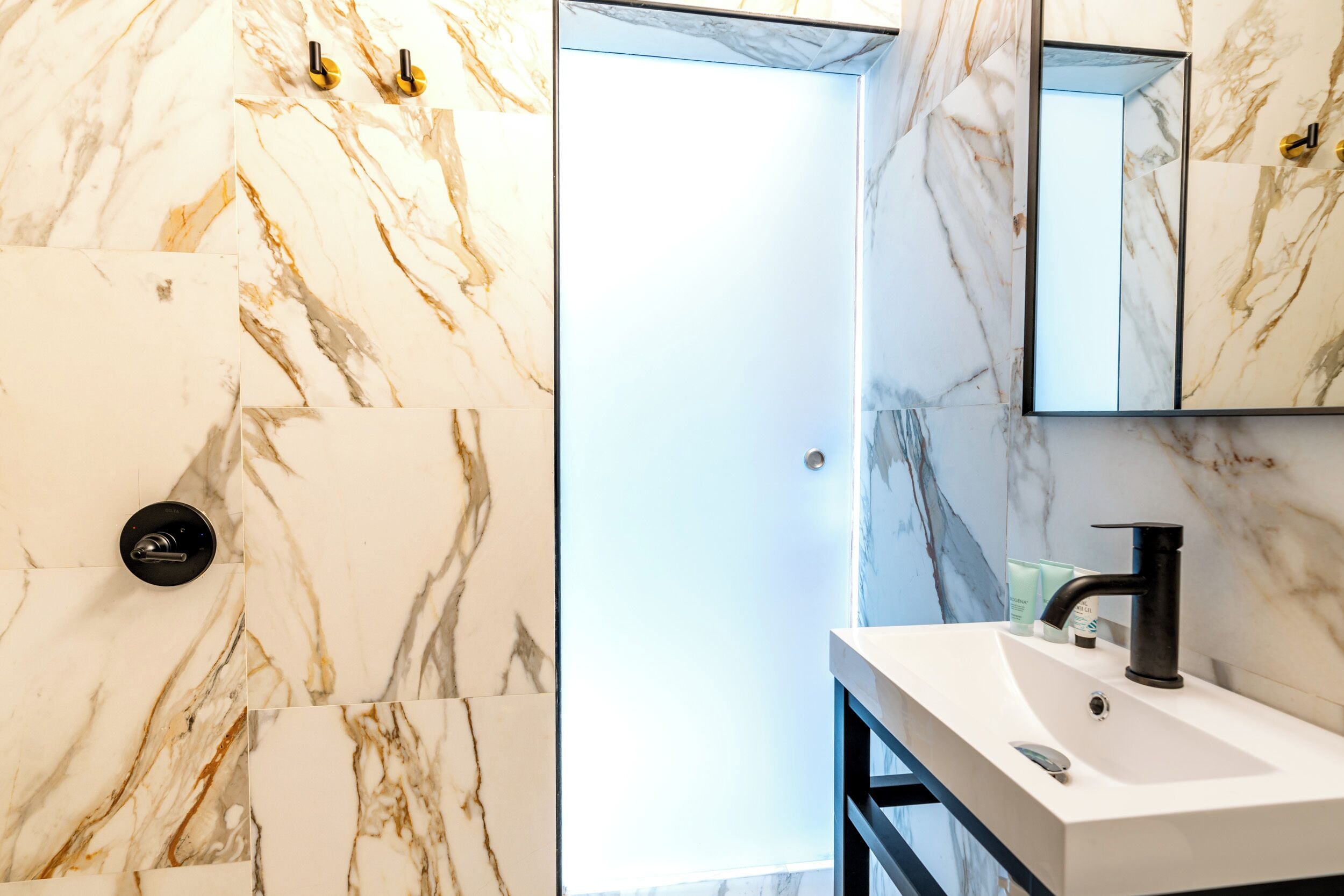 Ein Badezimmer mit Marmorwand, einem modernen Waschbecken und einem Spiegel.