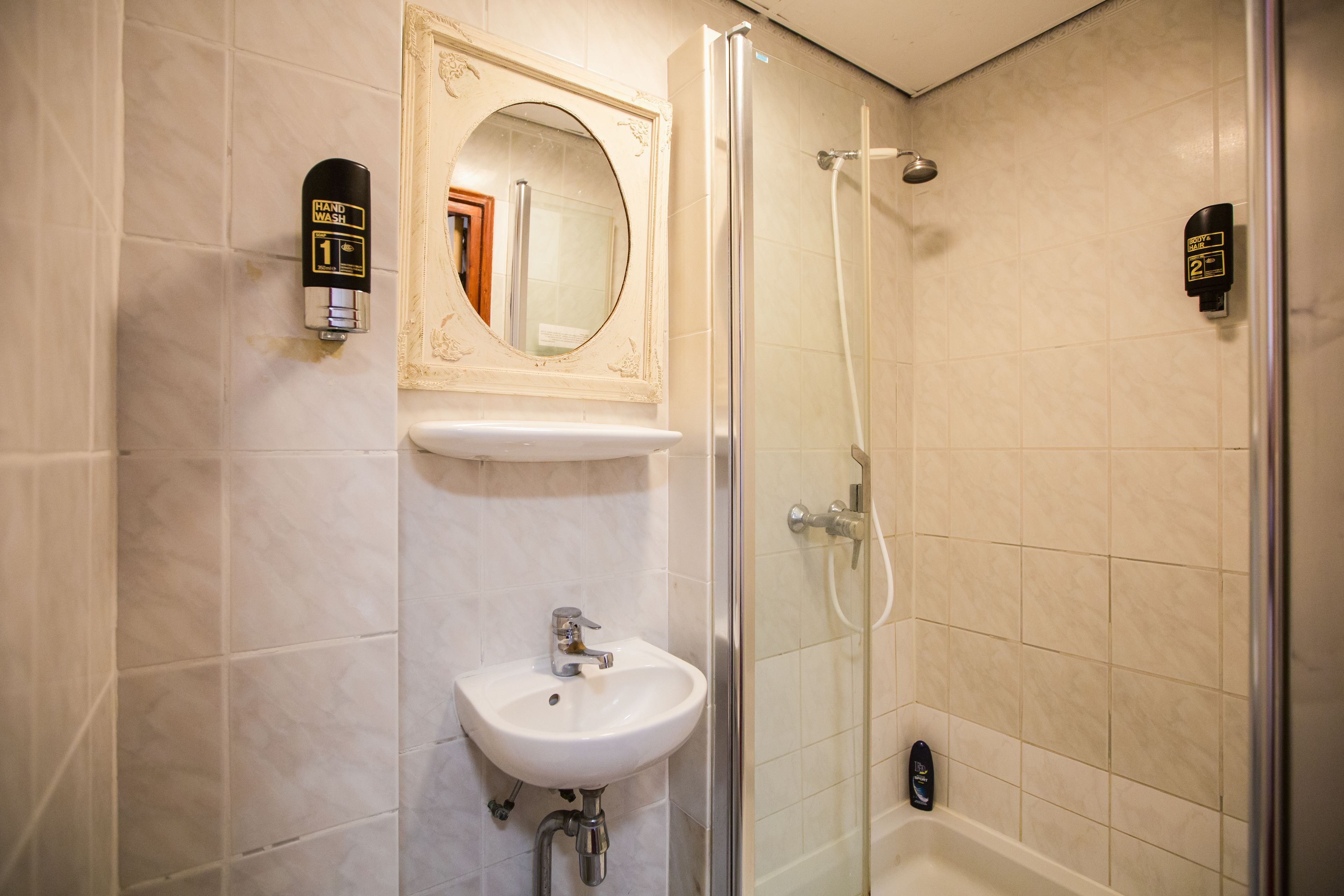 Ein Badezimmer mit Waschbecken, Spiegel und Dusche.