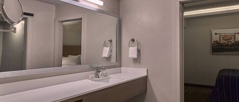 Une salle de bain avec un grand miroir, un lavabo et un porte-serviettes.