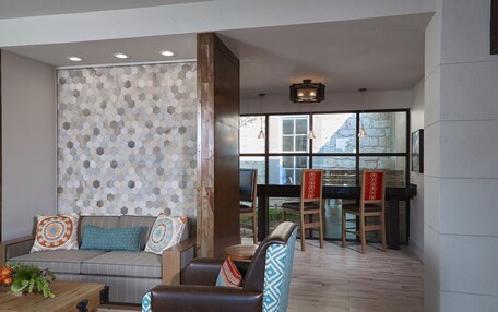 A modern living area with a sofa, armchairs, a coffee table, and a dining table with chairs.