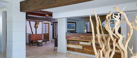 A spacious lobby with a wooden reception desk, a bench, and a deer head sculpture.