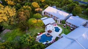 Vista aérea de una propiedad residencial con piscina, mobiliario exterior y un edificio grande de techo plano.
