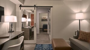Una habitación de hotel moderna con escritorio, silla, sofá y un espejo grande.
