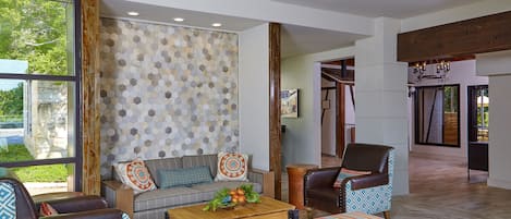 A spacious living room with a sofa, armchairs, a coffee table, and a patterned ottoman.