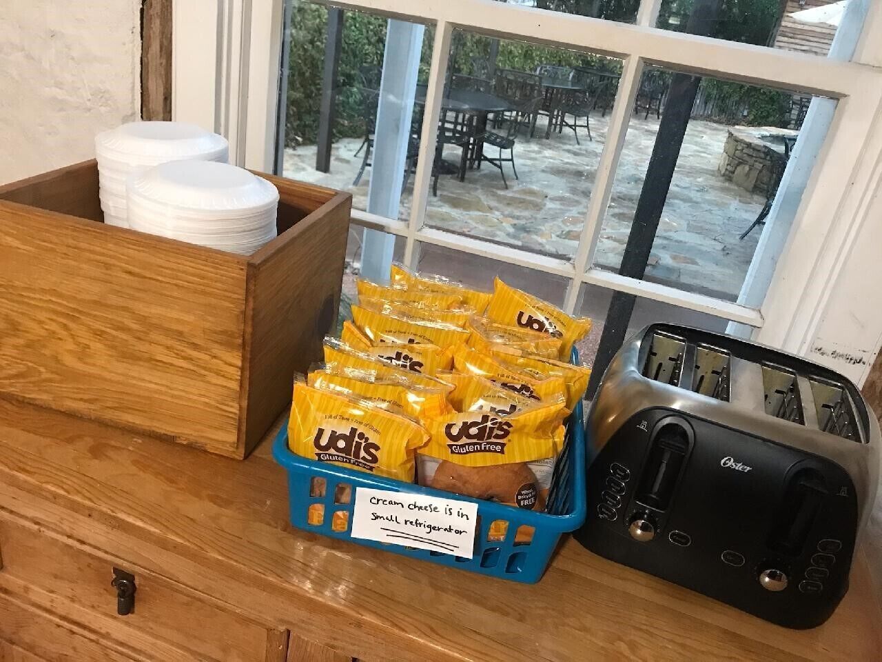 A kitchen counter with a toaster, a blue basket of Udi's gluten-free crackers, and a wooden box with white plates.