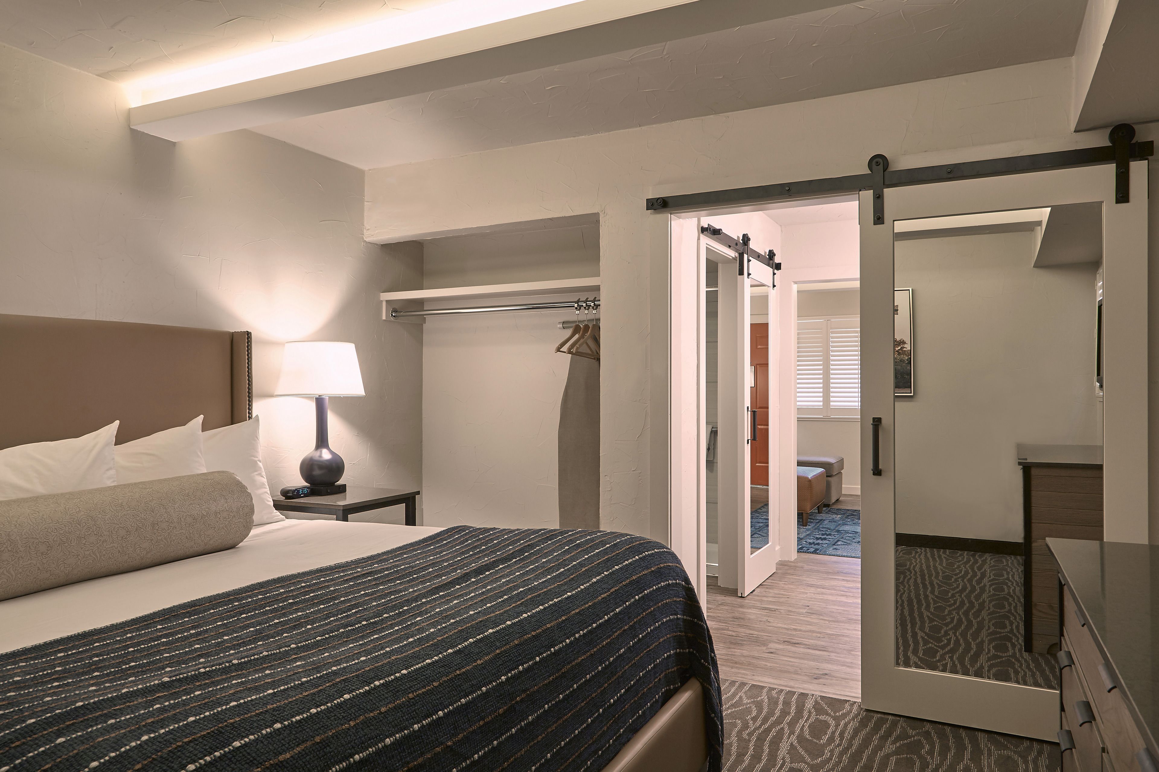 A hotel room with a bed, bedside table, lamp, and a wardrobe.
