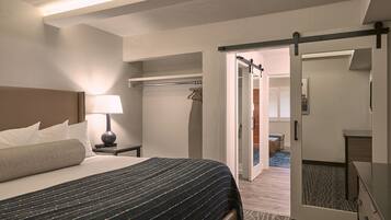 A hotel room with a bed, bedside table, lamp, and a wardrobe.