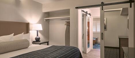 Een hotelkamer met een bed, nachtkastje, lamp en een kledingkast.