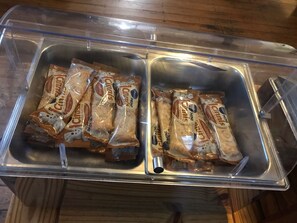 Un récipient transparent en plastique, doté de deux compartiments, chacun contenant plusieurs paquets de collations.