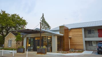 A modern building with a stone facade, large windows, and a red door.