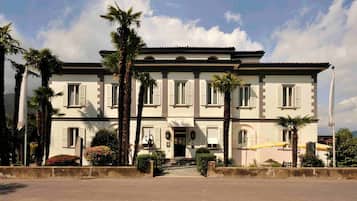 Stunning two-story building with a central entrance, flanked by columns, surrounded by lush greenery.